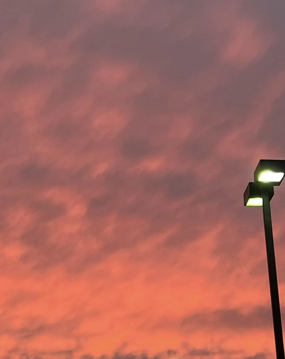 A picture of the sky when the sun is 
            	setting with a light pole